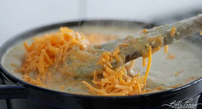 adding cheddar cheese to a broccoli soup