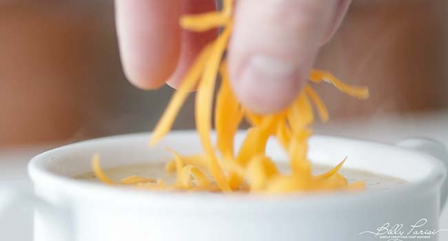 garnishing a soup with shredded cheddar cheese