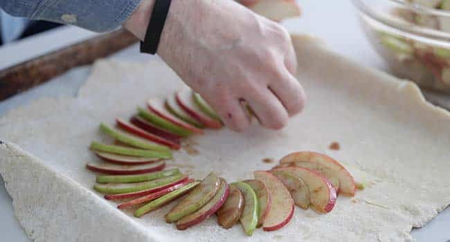 adding sliced apples to pie dough