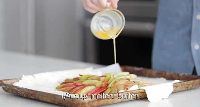 adding melted butter to the top of an apple galette