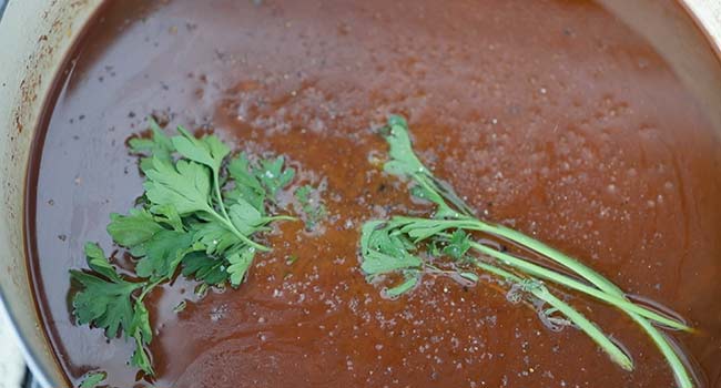 beef stock and herbs in a pot