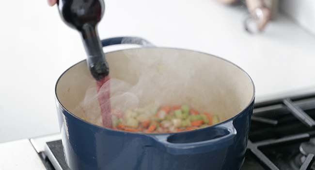 deglazing a pot of vegetables with red wine