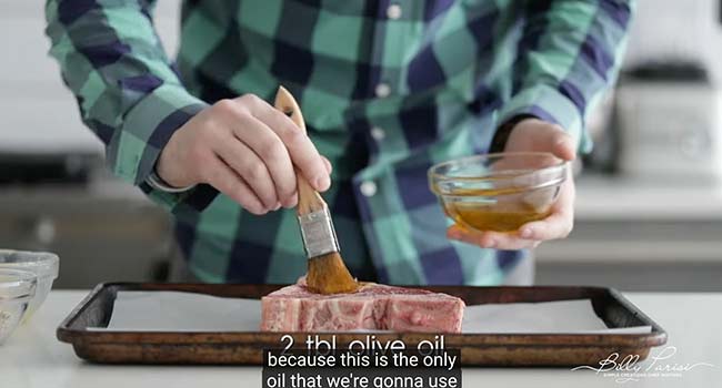 brushing a steak with olive oil