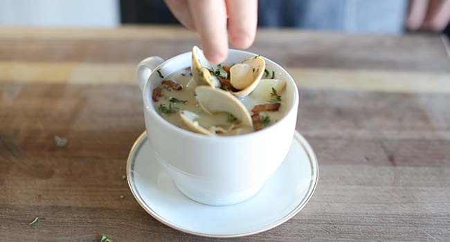 garnishing a bowl of a clam chowder