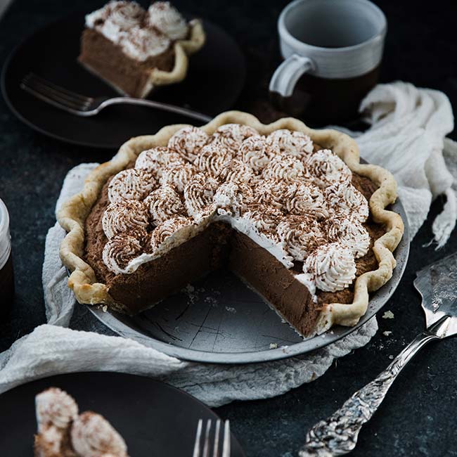 french silk pie recipe in a pie tin with whipped cream and chocolate shavings