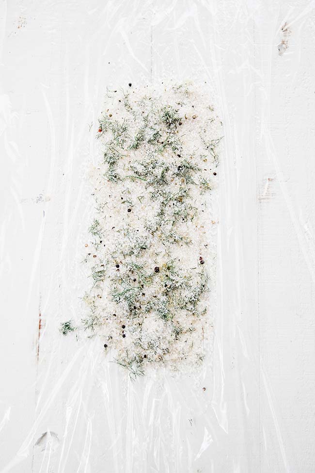spreading out the gravlax mixture onto a sheet of plastic wrap