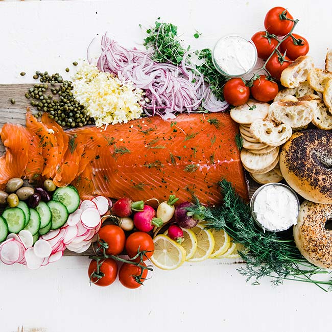 salt cured salmon gravlax spread with fruit, vegetables and bagels