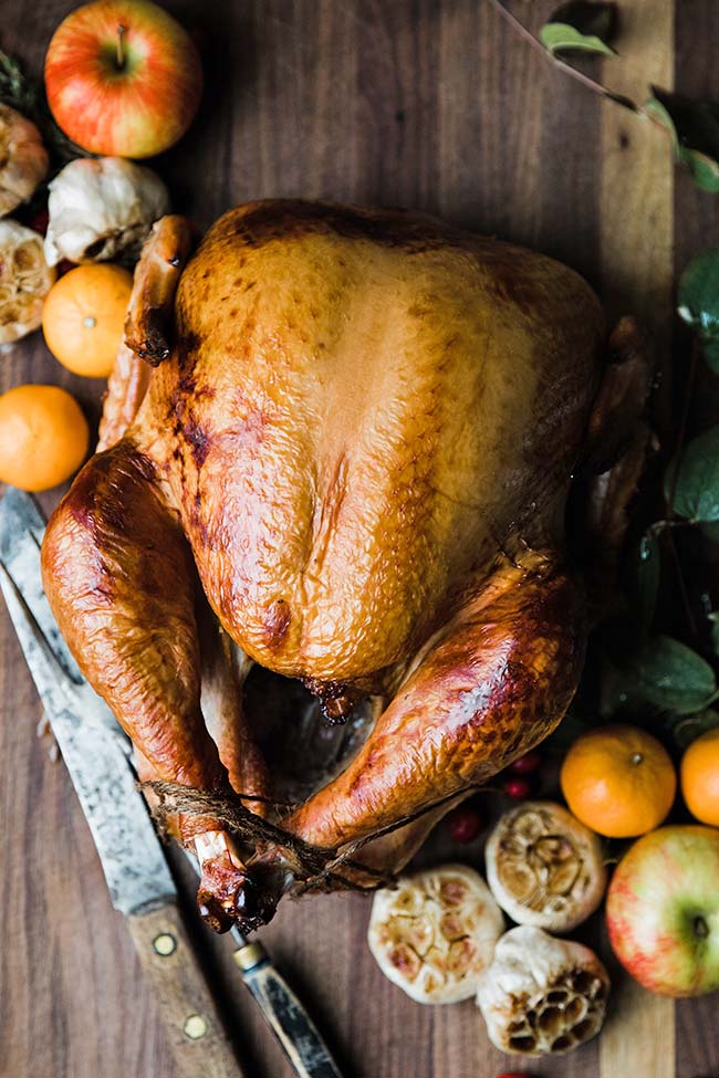 a cooked turkey with clementines and a carving knife