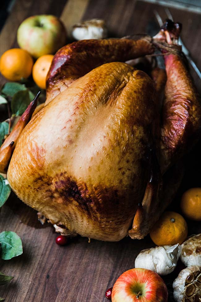 smoked turkey recipe with trussed legs next to fruit