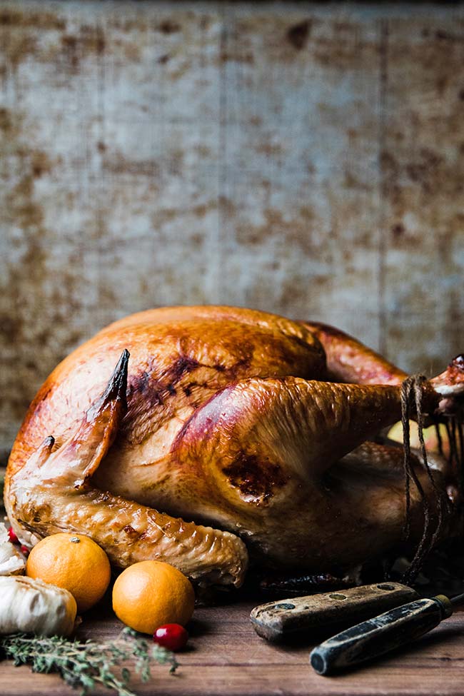 a smoked turkey that is brined on a cutting board with herbs