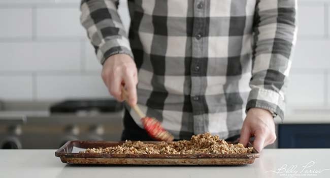 spreading out granola on a sheet tray