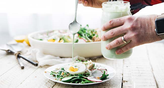 pouring dressing on a green goddess salad