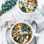 vegetable minestrone soup served in a large cup with herbs and bread