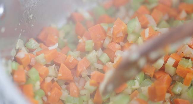 cooking onions, celery, and carrots in a pot