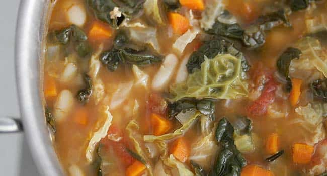 simmering kale and cabbage with vegetables in broth in a pot