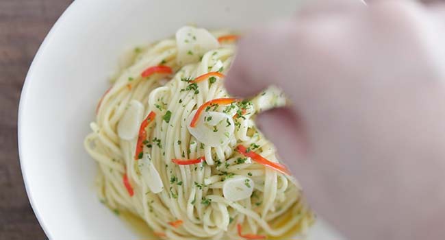 garnishing a spaghetti aglio e olio with parsely