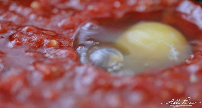 adding an egg to tomatoes