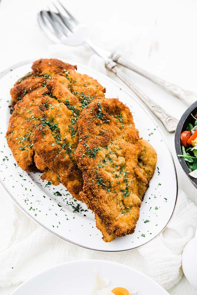 chicken cutlets for chicken milanese served on a platter with a garnish of parsley