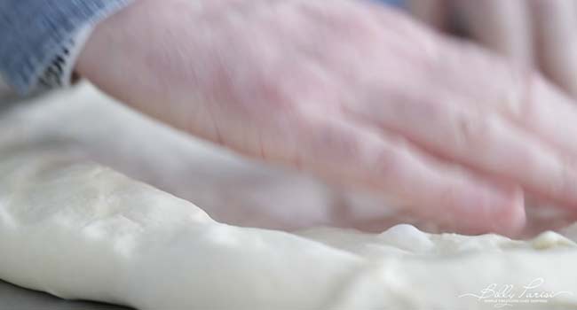 stretching focaccia dough on a sheet pan