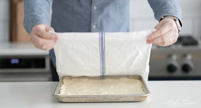 covering focaccia dough with a towel