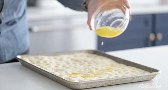 pouring salamoia onto focaccia dough