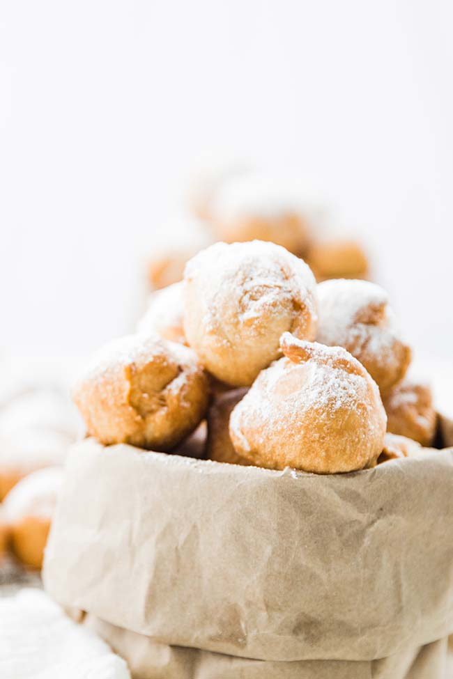 italian zeppoles coated in powdered sugar and placed in a brown paper bag