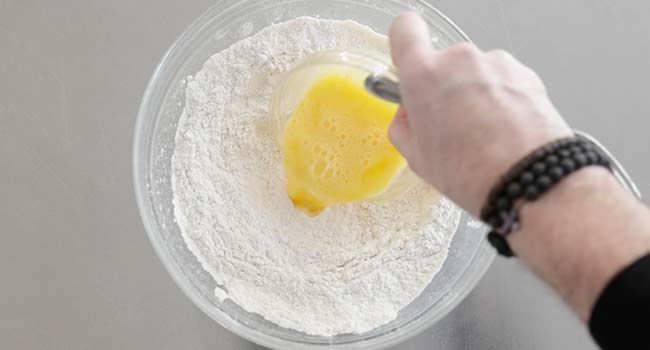 adding eggs to flour