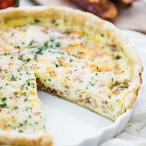 quiche lorraine recipe in a tart pan with a slice taken out