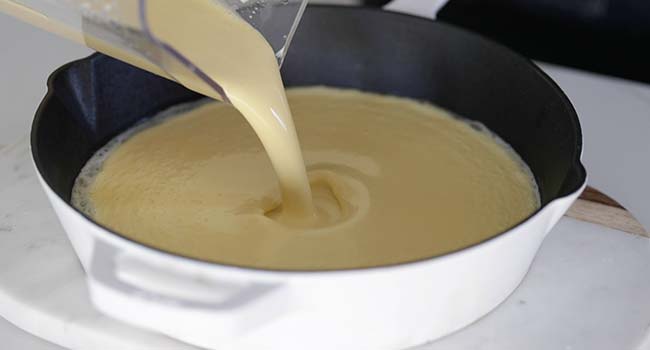 pouring batter into a cast iron skillet 