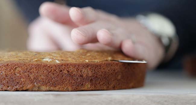 slicing the top off of a cake