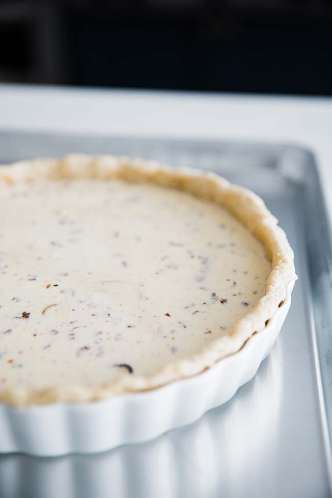 pre cooked quiche filling in a tart pan with parbaked pie crust