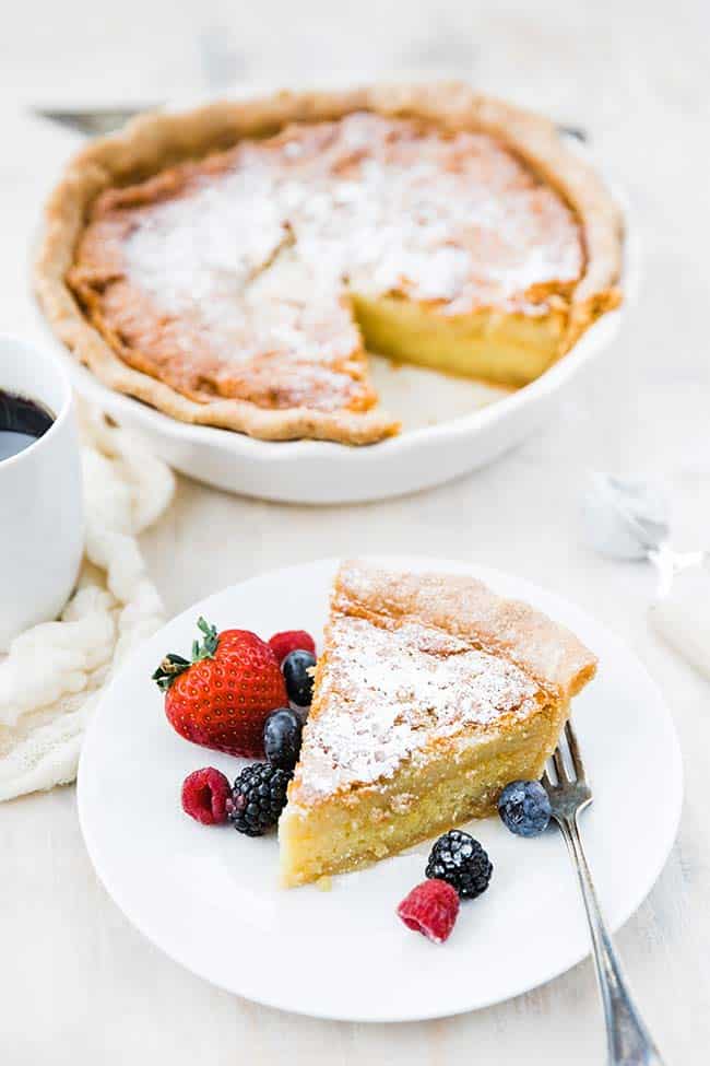 slice of chess pie with berries next to whole pie