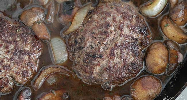 simmering beef in a gravy with mushrooms and onions