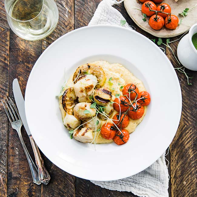 scallops with polenta and tomatoes on a plate