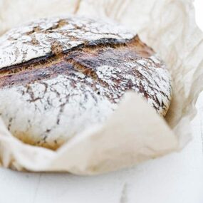 baked bread round wrapped in brown parchment paper