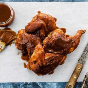 smoked chicken halves with bbq sauce on parchment paper