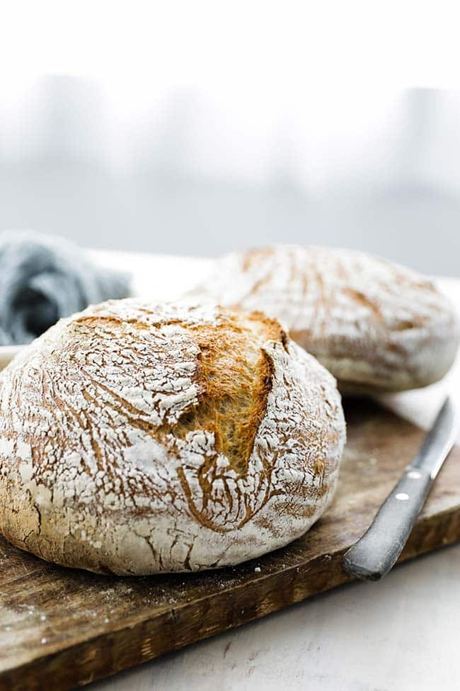 loaves of bread on a cutting board with a serrated knife