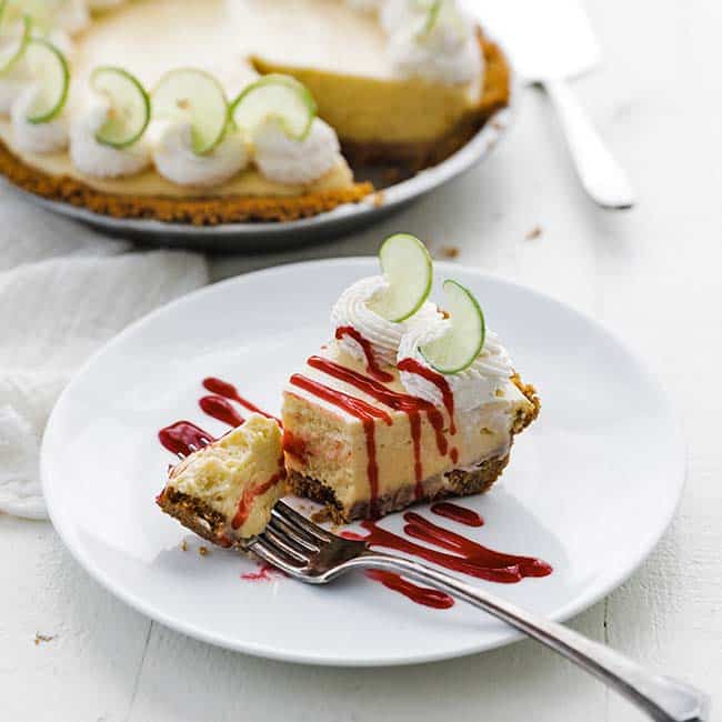 sliced of key eaten key lime pie with fork raspberry sauce and whole pie