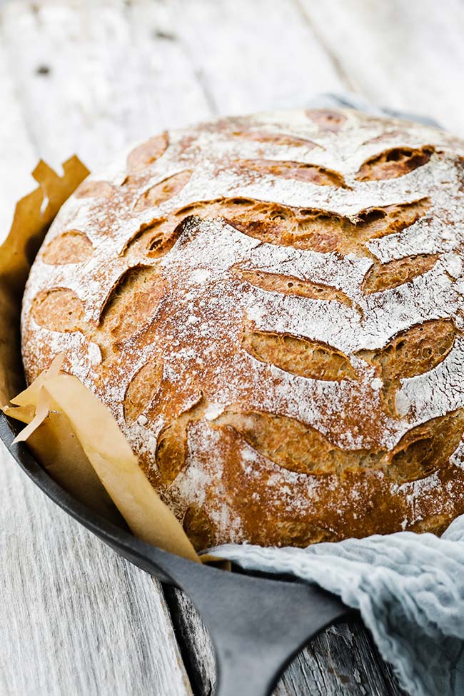 boule bread with designs in a skillet with parchment paper