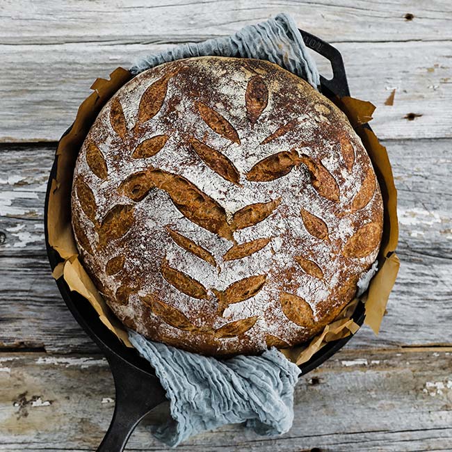 french boule bread in an iron skillet with parchment