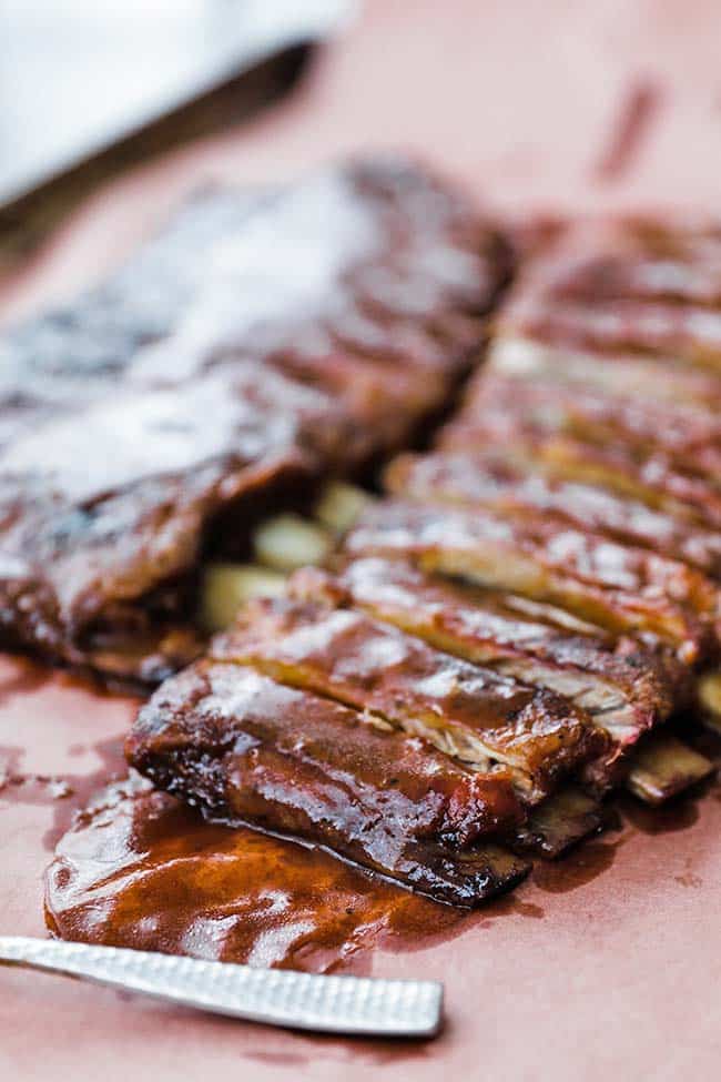 sliced bbq ribs with bones on paper with sauce