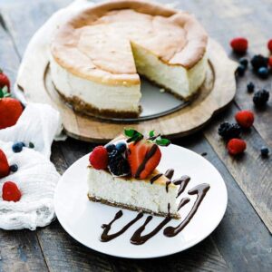 slice of cheesecake on a plate with berries and chocolate sauce