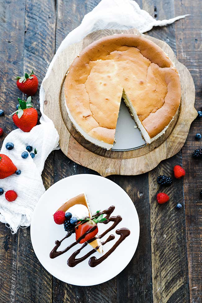 cheesecake slice alongside whole cheesecake with berries