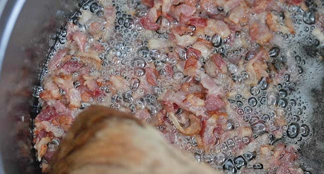 cooking bacon in a pot until crispy