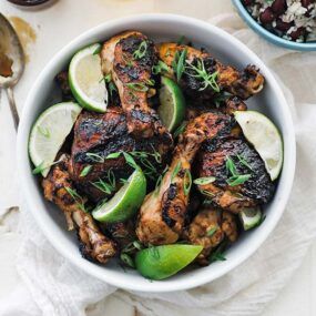 bowl of grilled jerk chicken with limes