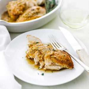 sliced cooked chicken breast on a plate with sauce