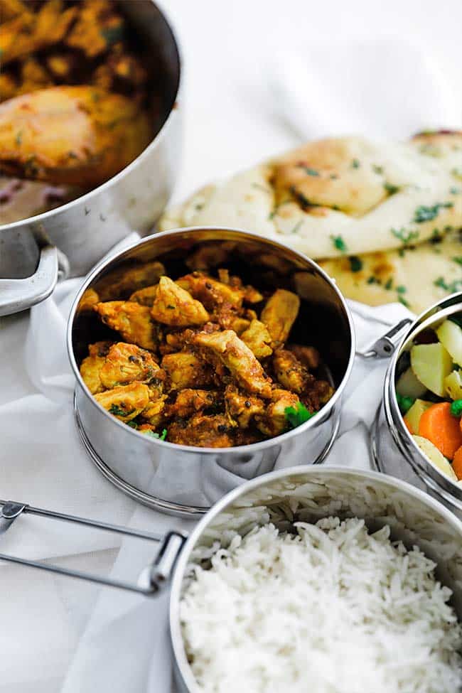 curry chicken in container next to rice and veggies