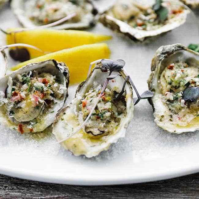 oysters on a plate with butter and lemons