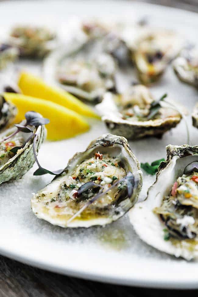 platter of cooked oysters on the half shell with lemon
