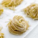 curled up raw spaghetti noodles on parchment